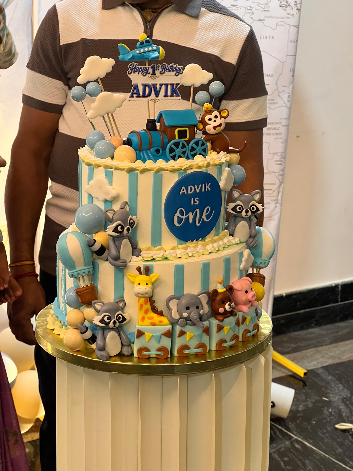 Two-tier first birthday cake featuring animal train and blue airplane