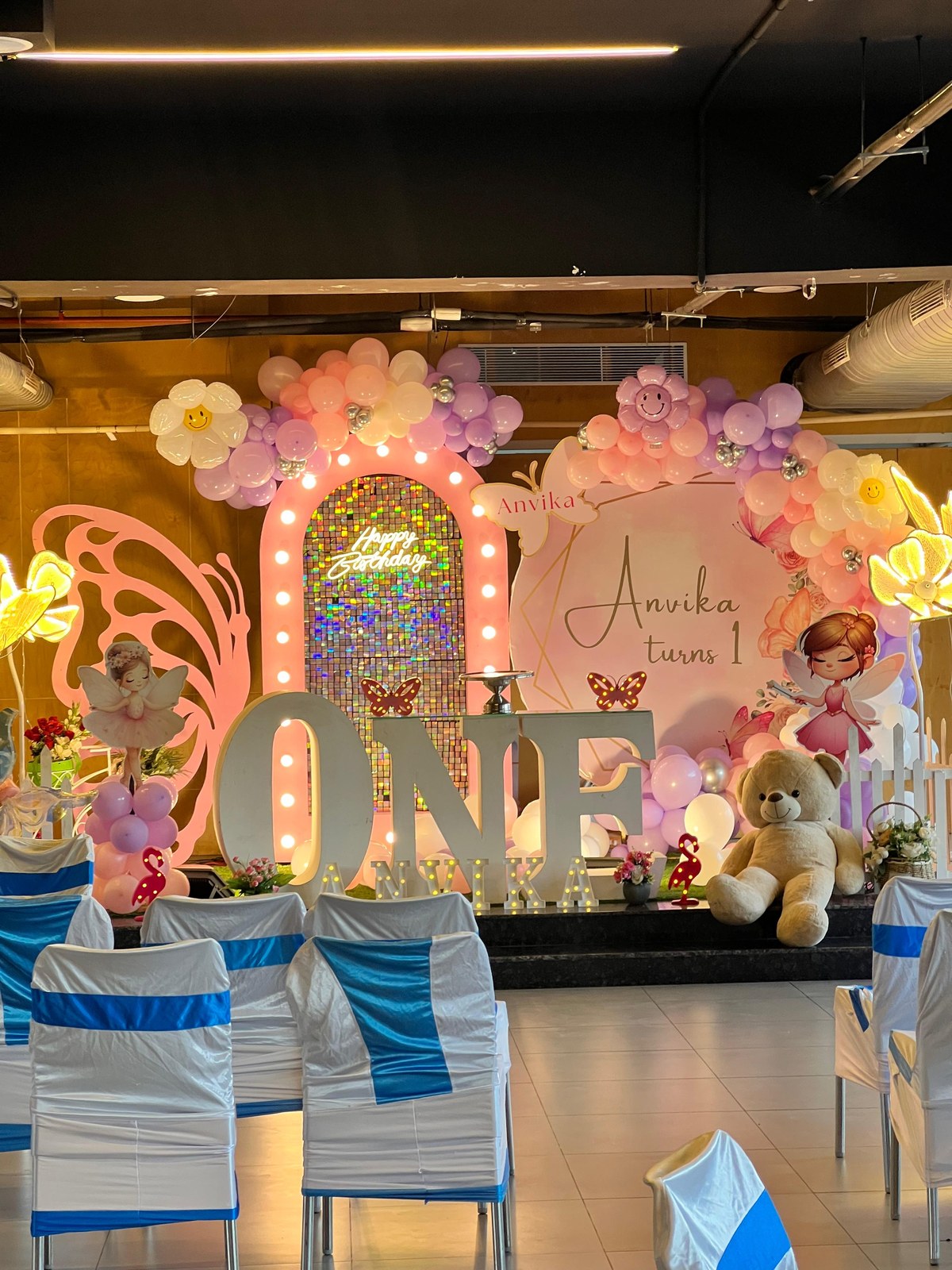Full birthday stage decor with illuminated shimmer backdrop and giant ONE letters