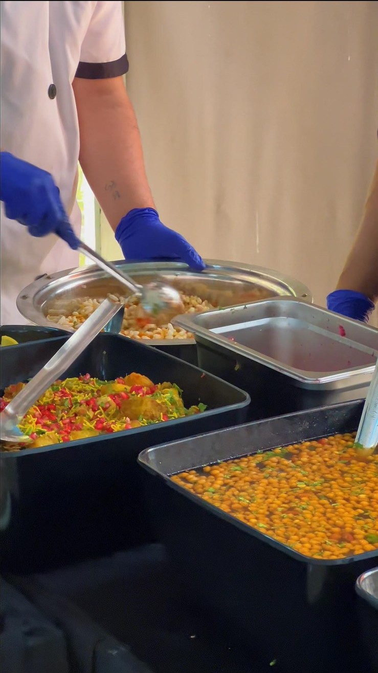 Professional chef serving fresh bhel and savory snacks at live chaat counter